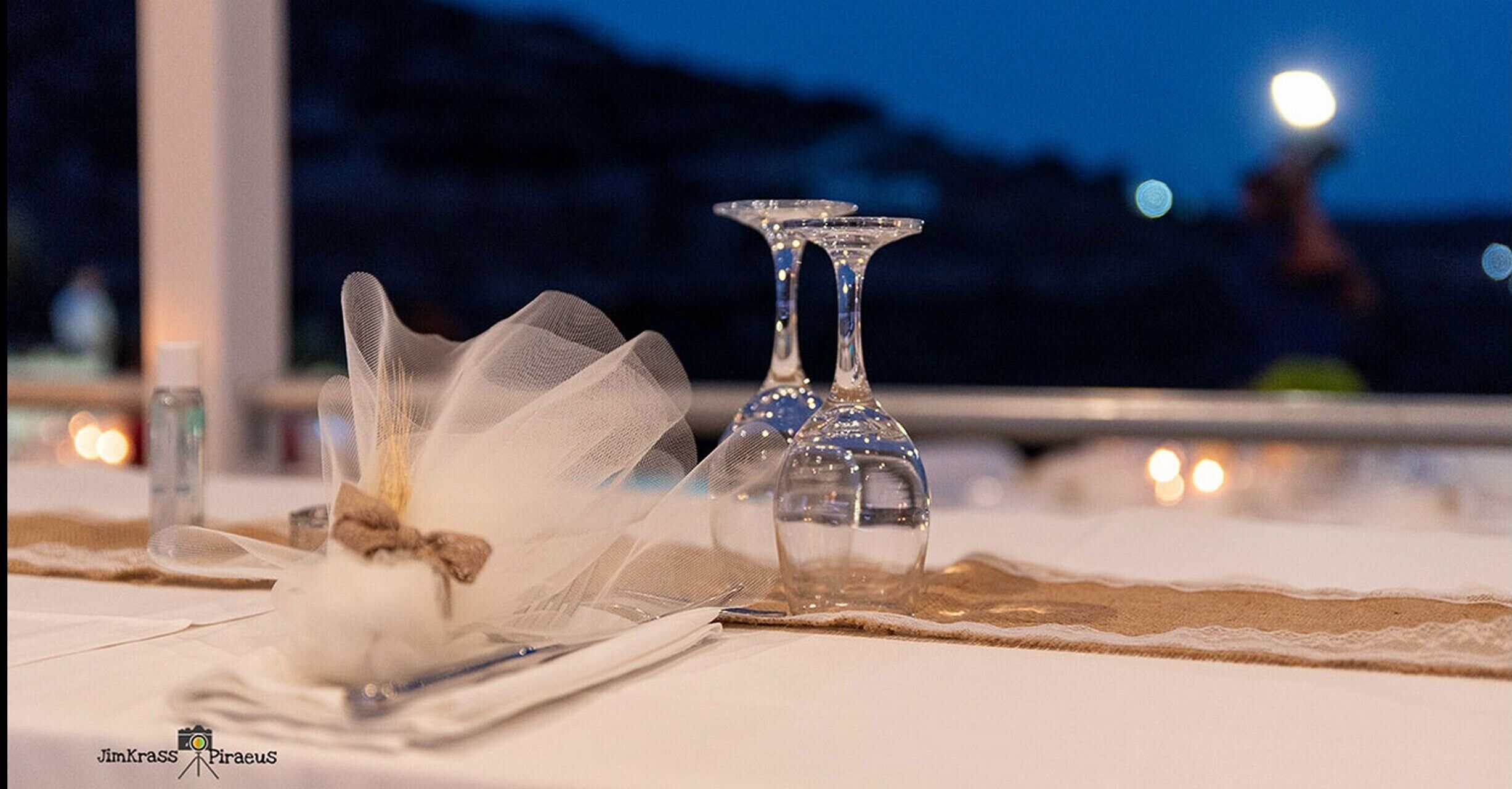 A table set with a glass, a glass with a stem, and a glass with a stem and a base, with a blurred background.