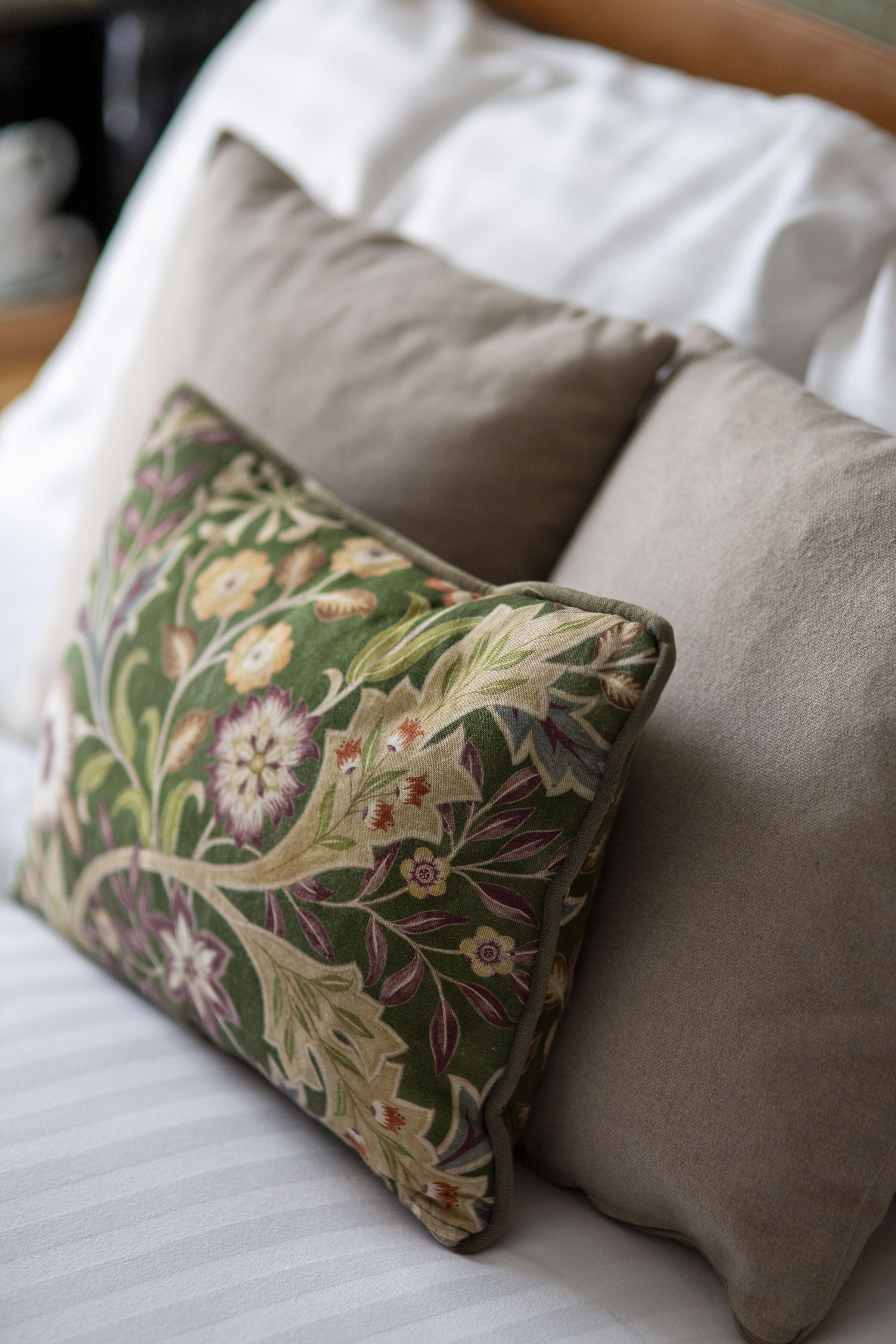Een bed met twee kussens, waarvan één een bloemenpatroon heeft en de ander effen is.