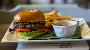 Una hamburguesa acompañada de papas fritas y una ensalada pequeña sobre un plato blanco.