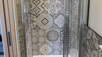 A shower with patterned tiles and a clear glass door.