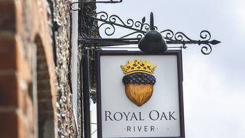 Segnaletica con la scritta 'Royal Oak River' e un emblema con una corona, fissata a un edificio in mattoni con insegna in ferro battuto.