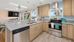 A modern kitchen with a dishwasher, oven, and granite countertop. - Waterfront Fishing Cottage, 2 King Beds, 75in HDTV, Family Friendly (Jacksonville)