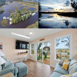 Un interior moderno con un sofá, televisor y ventanas amplias con vistas a un paisaje natural.
