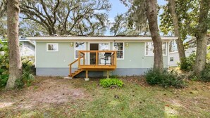A single-story house with a front porch, a small deck, and a staircase leading to the front door. - Waterfront Fishing Cottage, 2 King Beds, 75in HDTV, Family Friendly (Jacksonville)