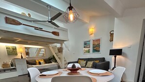 Een moderne eetruimte met een ronde tafel, witte stoelen en een houten vloer.