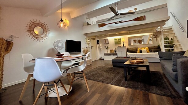 Een moderne woonkamer met een eethoek, een trap en een keuken.