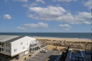 Un hotel frente a la playa con estacionamiento, un edificio blanco y vistas al océano.