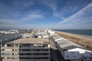 A coastal hotel with multiple floors, balconies, and a view of the beach and ocean.