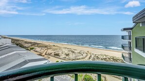 A beachfront hotel with a view of the ocean, a sandy beach, and a parking lot.