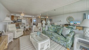 A spacious living area with a sofa, chairs, a coffee table, and a television.