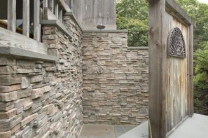 Parede de pedra com porta de madeira e um detalhe decorativo de metal.