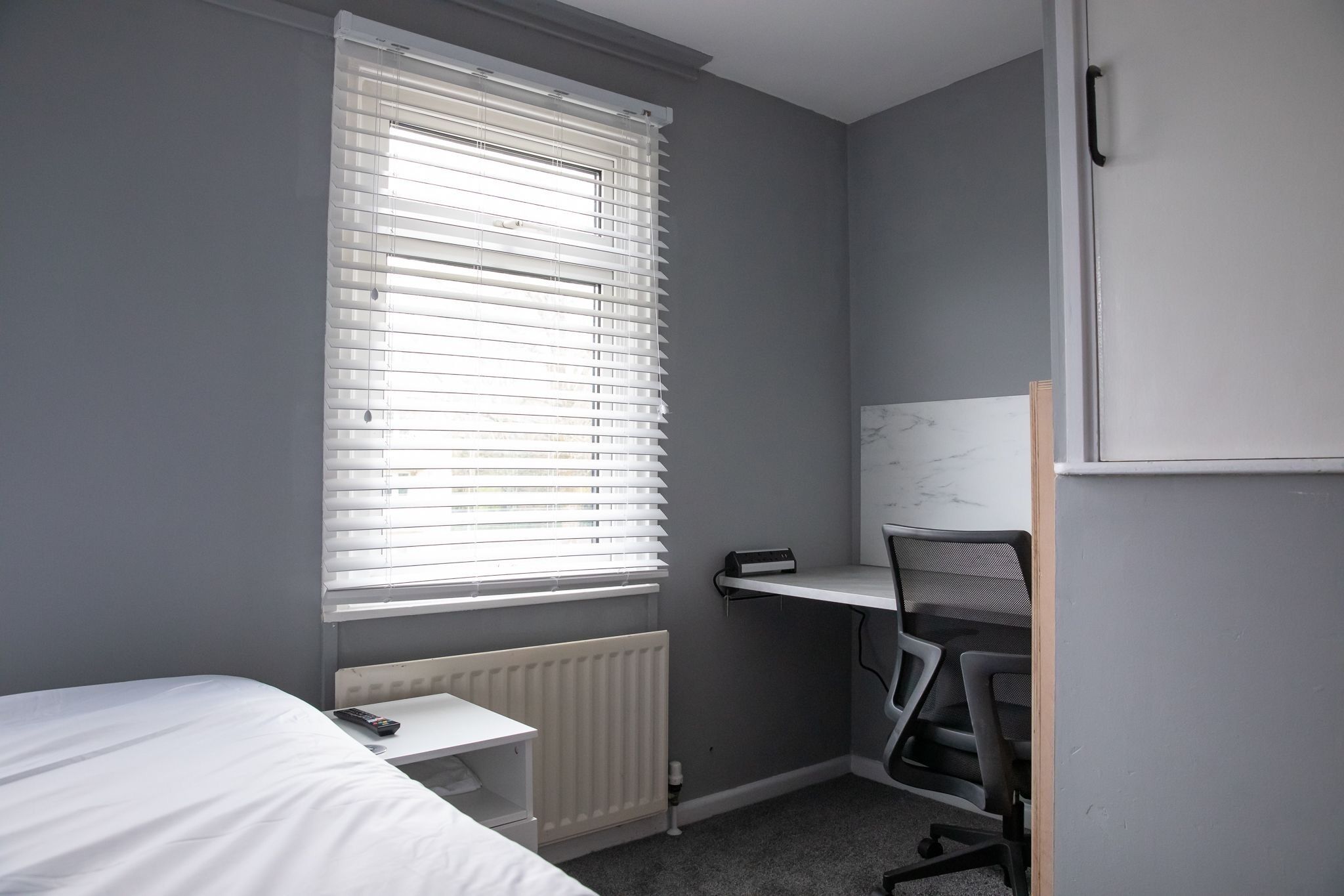 A bedroom with a bed, a desk, and a chair.