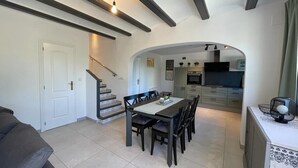 A dining area with a table and chairs, a kitchen in the background, and a staircase leading to another level. - T-0621, Campo Olivar, townhouse in Campo Olivar, Els Poblets (els poblets)
