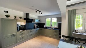 A modern kitchen with light green cabinets, a built-in oven, and a dining area with a table and chairs. - T-0621, Campo Olivar, townhouse in Campo Olivar, Els Poblets (els poblets)