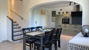 A dining area with a table and chairs, a kitchen in the background, and a staircase. - T-0621, Campo Olivar, townhouse in Campo Olivar, Els Poblets (els poblets)