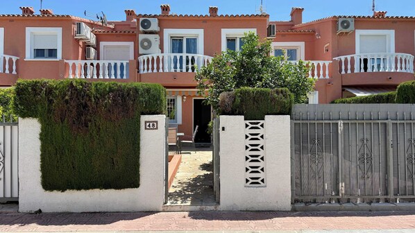 A residential building with a gated entrance, numbered 48, and a paved pathway leading to the door.