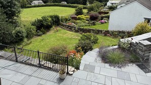 A residential area with a well-maintained lawn, stone pathways, and a variety of flowering plants.