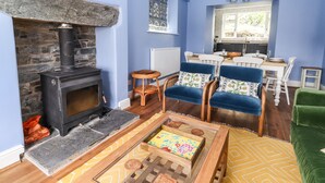 A living room with a stone fireplace, blue walls, a dining area with white chairs, and a green sofa.