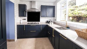 A modern kitchen with dark cabinetry, a gas stove, and a window providing a view of greenery.
