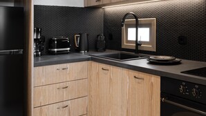 Een moderne keuken met houten kastjes, een zwarte koelkast, een koffiezetapparaat, een broodrooster en een zwarte oven.