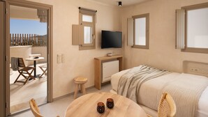 Een slaapkamer met een bed, een televisie, een klein tafeltje met twee kopjes, een houten stoel, een bureau en een raam.