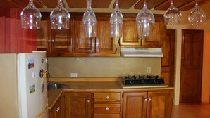 Una cocina con gabinetes de madera, un refrigerador, una estufa y lámparas colgantes.