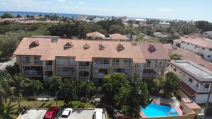 Un hotel de varios pisos con techo de tejas rojas, balcones y una piscina.