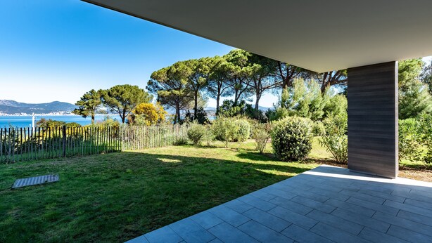 Un patio moderno al aire libre con vistas al mar y árboles.