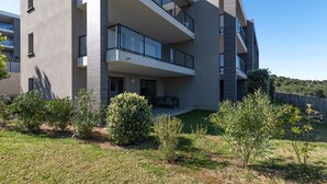Un edificio residencial moderno de varios pisos con balcones, un césped cuidado y zonas verdes circundantes.