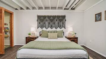 A bedroom with a bed, bedside tables, a wall tapestry, and a wooden door.