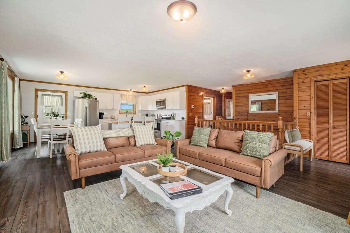 A cozy living room with two sofas, a coffee table, and a television in the background.