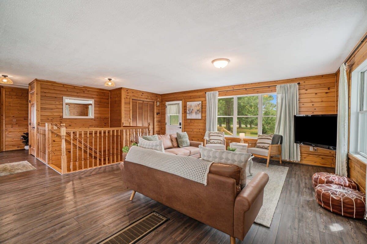 A cabin interior with a wooden interior, a sofa, a television, and a staircase.