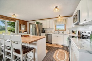 A modern kitchen with white cabinets, a wooden island, and a stainless steel refrigerator.