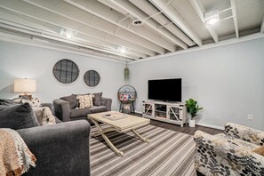 A modern living room with a sofa, coffee table, and television. - Hot Tub! | Pet Friendly! | Game Room! (Traverse City)
