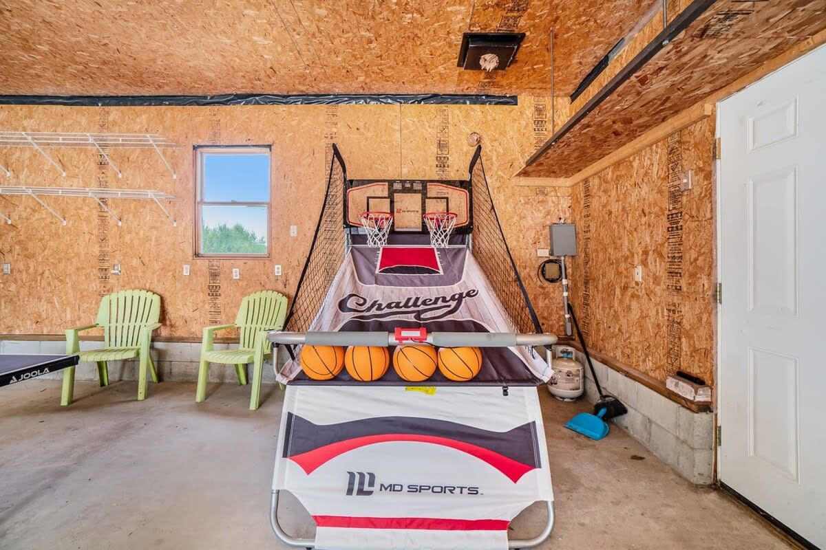 A basketball court with a net, two chairs, and a table with basketballs.
