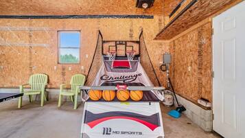 A basketball court with a net, two chairs, and a table with basketballs.