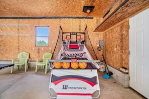A basketball court with a net, two chairs, and a table with basketballs. - Hot Tub! | Pet Friendly! | Game Room! (Traverse City)