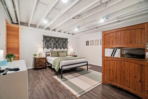 A bedroom with a bed, bedside tables, a wooden wardrobe, and a hanging tapestry. - Hot Tub! | Pet Friendly! | Game Room! (Traverse City)