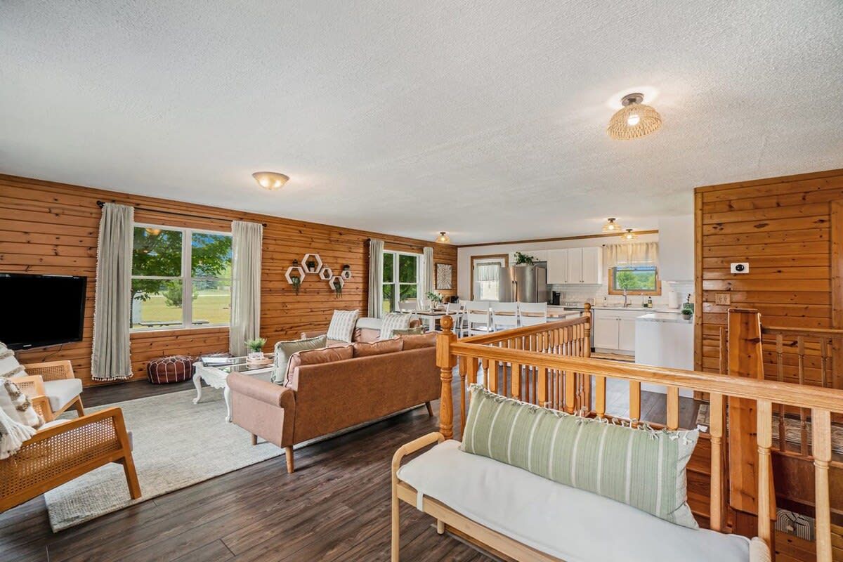 A wooden interior with a living area, kitchen, and a balcony.