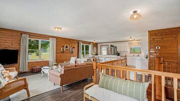 A wooden interior with a living area, kitchen, and a balcony.