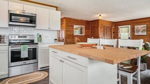 A modern kitchen with white cabinets, stainless steel appliances, and a wooden island. - Hot Tub! | Pet Friendly! | Game Room! (Traverse City)