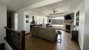 A spacious living room with a large sofa, a fireplace, and a television mounted on the wall. - Entire house oasis for EAA (Appleton)