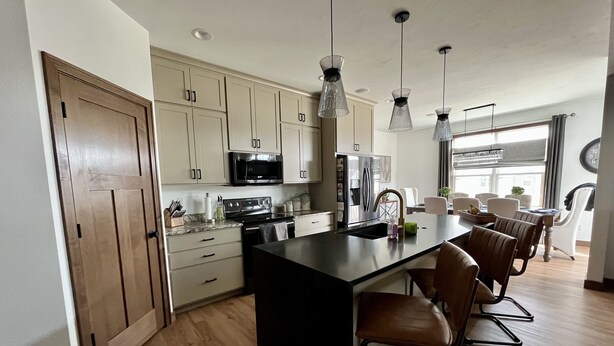 A modern kitchen with a central island, wooden cabinets, stainless steel appliances, and pendant lighting. - Entire house oasis for EAA (Appleton)