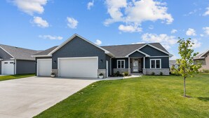 A modern two-story house with a garage, a well-maintained lawn, and a small tree. - Entire house oasis for EAA (Appleton)