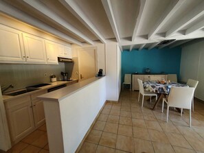 A compact kitchen with white cabinets, a central island, and a dining area with a table and chairs.