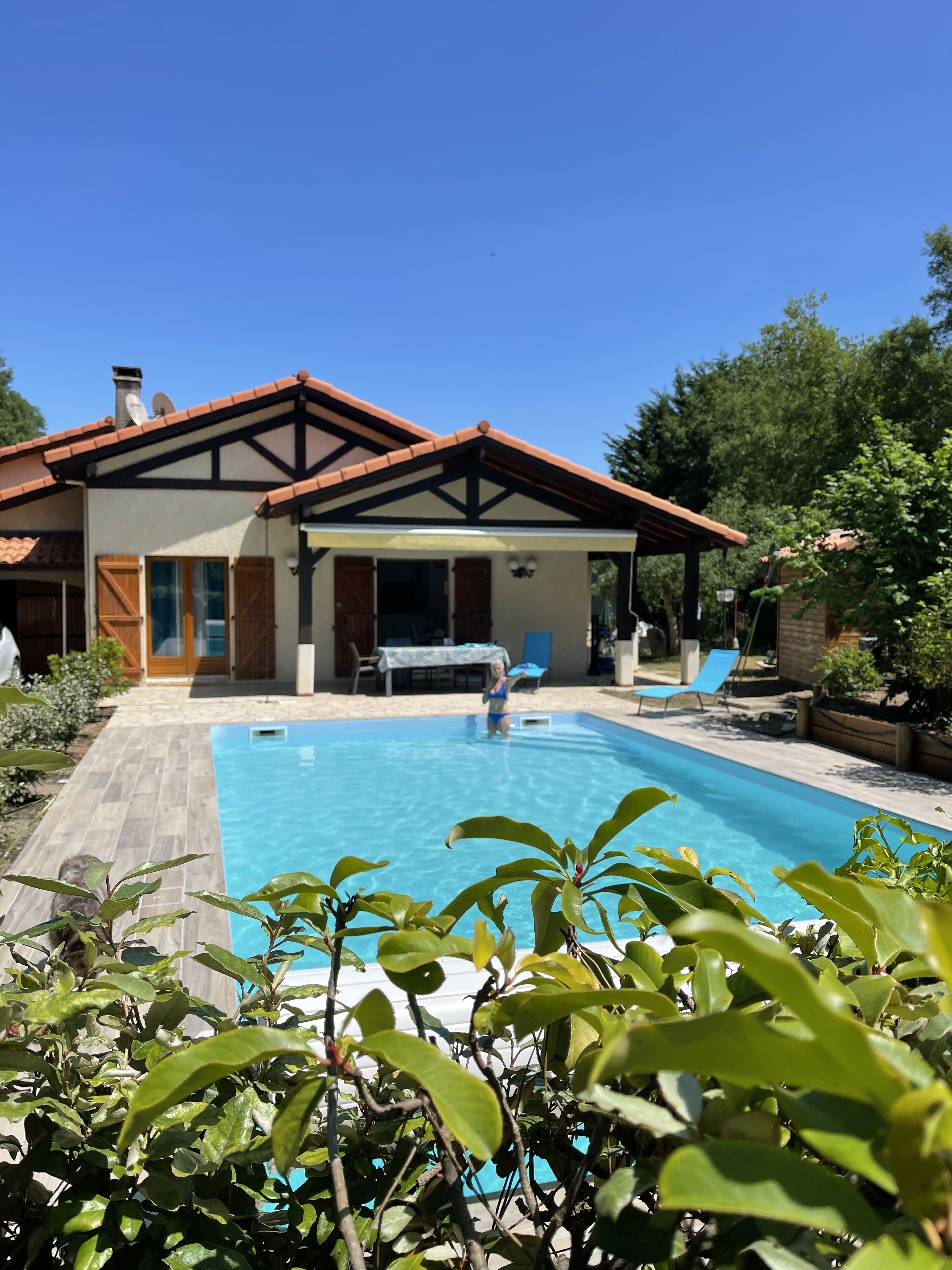A house with a swimming pool, a covered patio, and a garden.