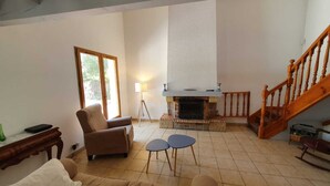 Ein Wohnzimmer mit Kamin, einer Holztreppe und einem Sofa.