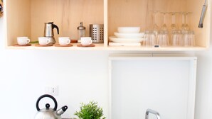 A kitchen with wooden shelves, a kettle, a coffee maker, and glassware. - Benedettini - Suites (Catania)
