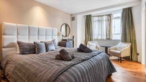 Ein modernes Hotelzimmer mit einem großen Bett, einem runden Spiegel, einem kleinen Tisch und einem Sessel.