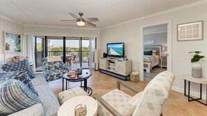 Un vaste espace de vie comprenant un téléviseur, des sièges et un balcon avec vue.